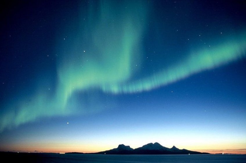 The Northern Lights over a mountainous landscape at twilight. 3
