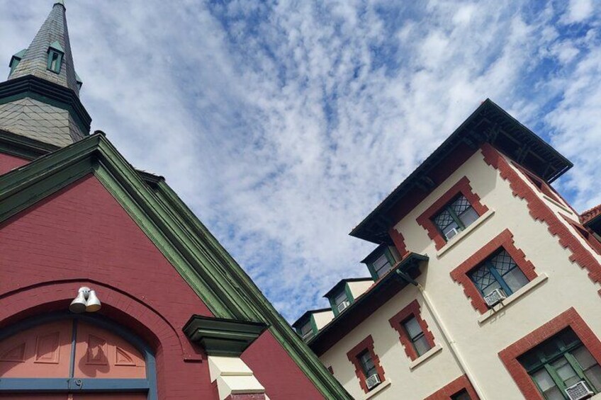 Un edificio rojo con techo verde y un edificio blanco con detalles rojos. 3