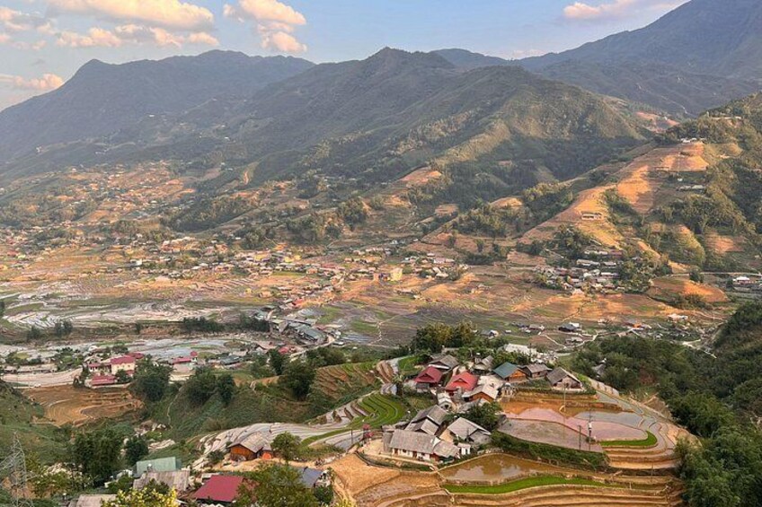 A mountainous landscape with terraced fields, scattered houses, and a winding road. 3