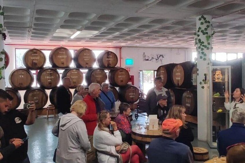 Een groep mensen in een kamer met houten vaten aan de muur. 2