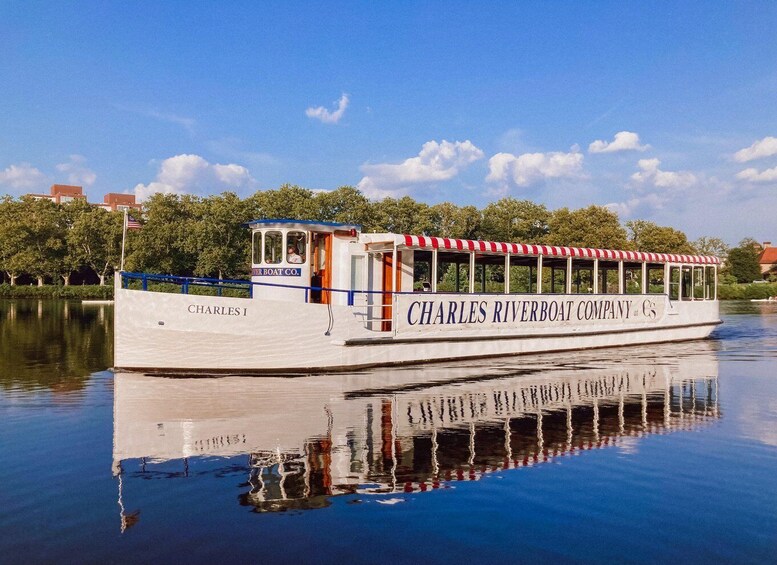 A white riverboat named 'Charles Riverboat Company' with 'Charles I' written on its side, docked at a calm river with trees and buildings in the background. 4