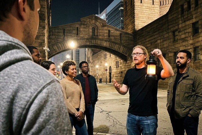 Un groupe de personnes se tient dans une rue, de nuit, avec un bâtiment historique en arrière-plan. 4