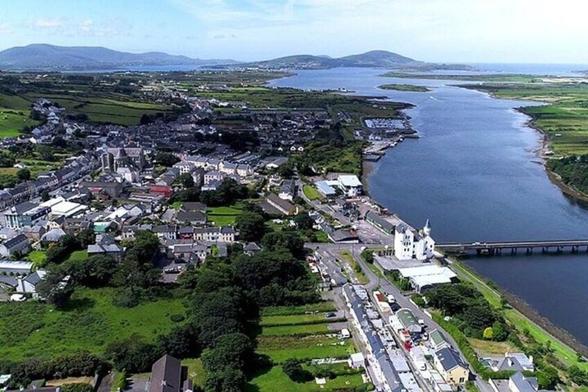 Une vue aérienne d’une ville côtière, avec une rivière, un pont et une église imposante. 1