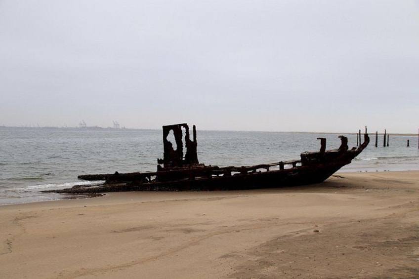 Ein versunkenes Schiff am sandigen Strand, das Meer im Hintergrund. 2