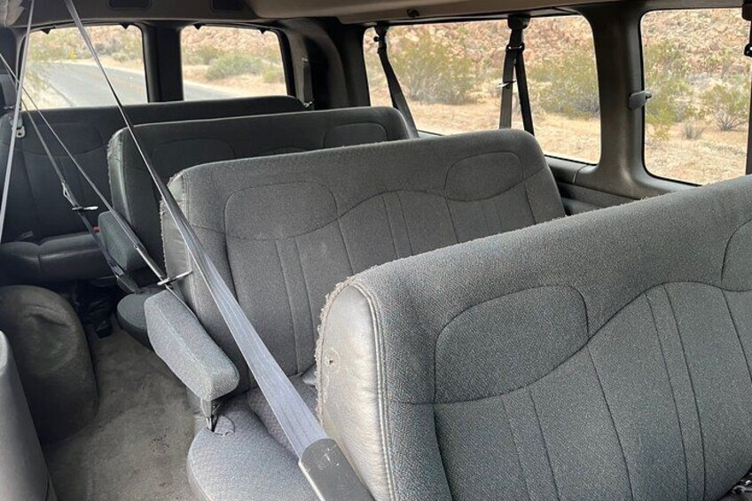 The interior of a vehicle with grey seats and a visible seatbelt. 2
