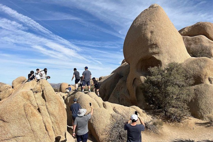 A group of people hiking on large rock formations with a clear sky. 4