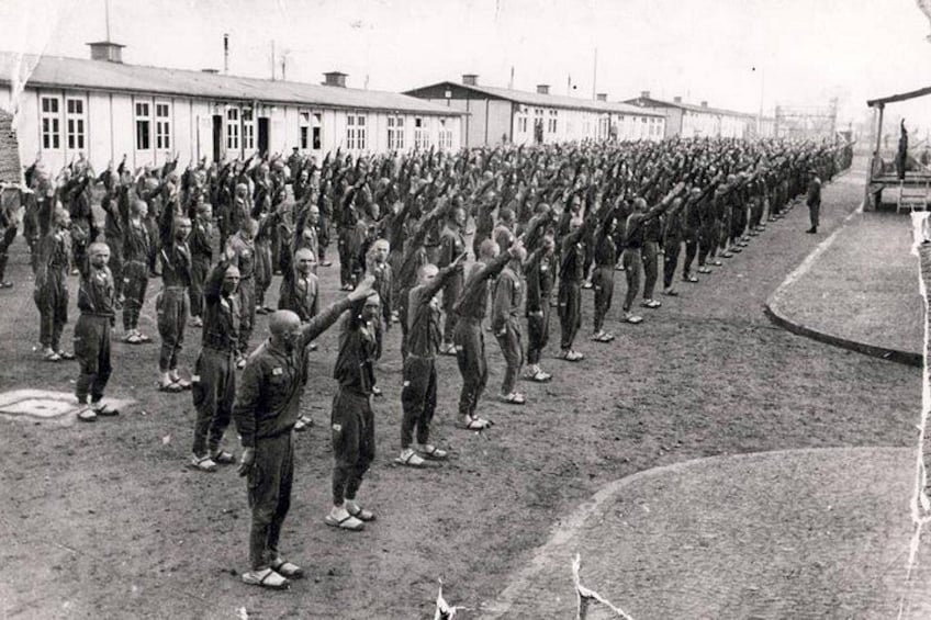Een grote groep mensen in uniform staan in een formatie, gericht op een gebouw. 1