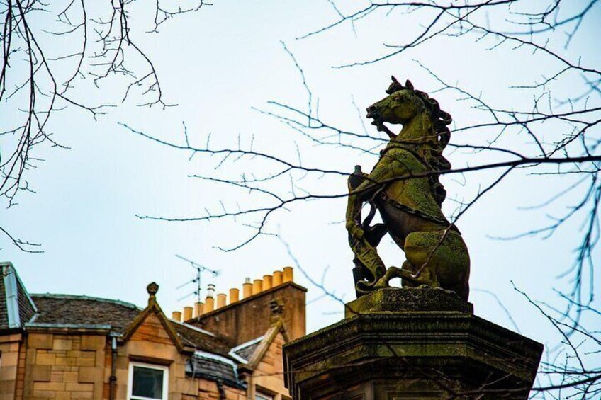 A bronze equestrian statue atop a stone pedestal, with a building in the background. 2
