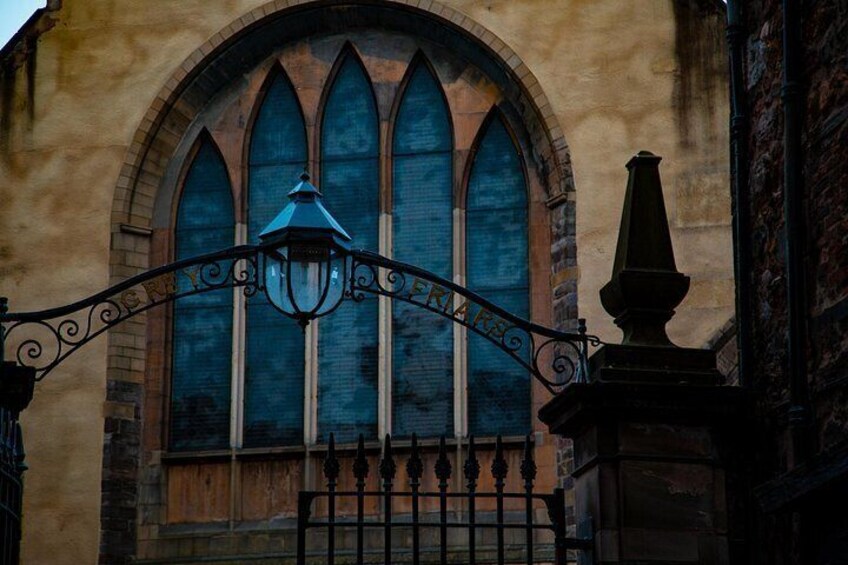 A gothic window with a pointed arch, a wrought iron gate, and a street lamp. 3