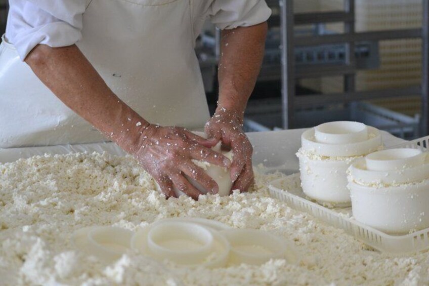 A person kneading dough on a table with flour scattered around and several white bowls. 1