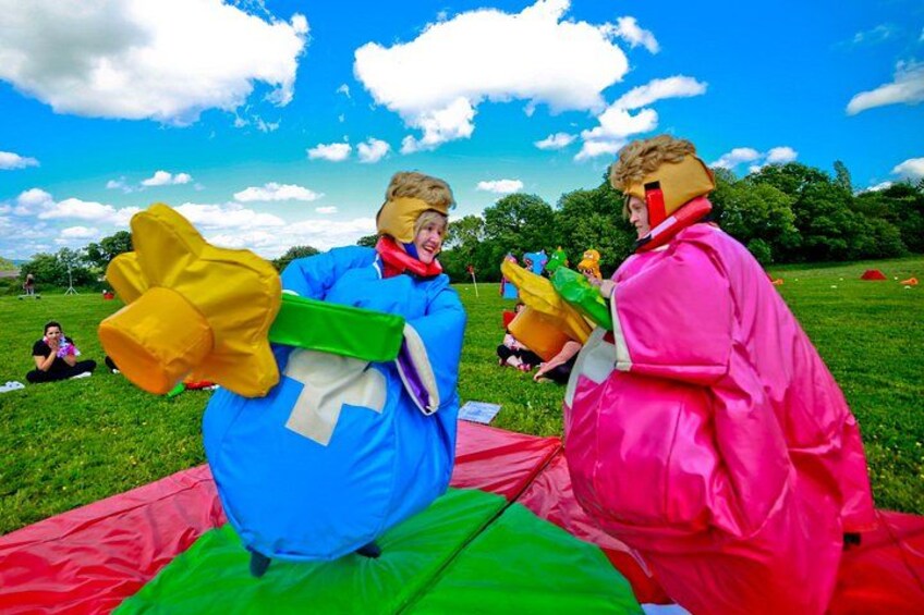 Two people in colorful costumes on a grassy field with a blue sky. 2