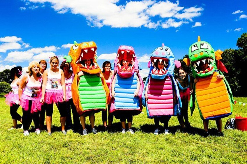 A group of people in colorful dragon costumes standing in a grassy field. 2