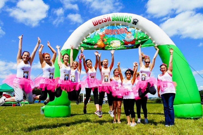 A group of people in a field with a green inflatable arch and a banner that says 'Welcome'. 1