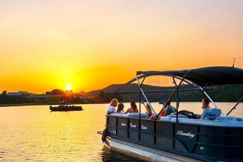 Ein Boot mit Passagieren bei Sonnenuntergang, im Hintergrund eine Brücke und ein ruhiger Fluss. 1