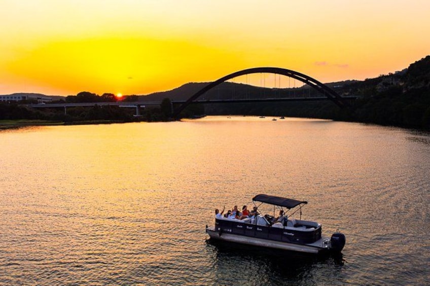 Ein Sonnenuntergang über einem Fluss mit einem Boot, das Personen befördert, einer Brücke im Hintergrund und Hügeln. 3