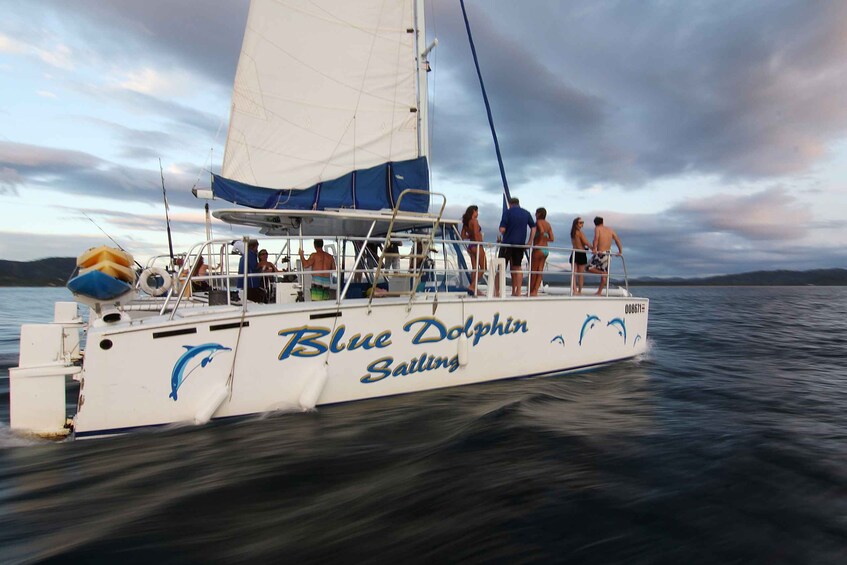A sailboat named 'Blue Dolphin Sailing' with people on board, sailing on a body of water. 1