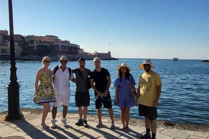 A group of people standing by a waterfront with buildings in the background. 2