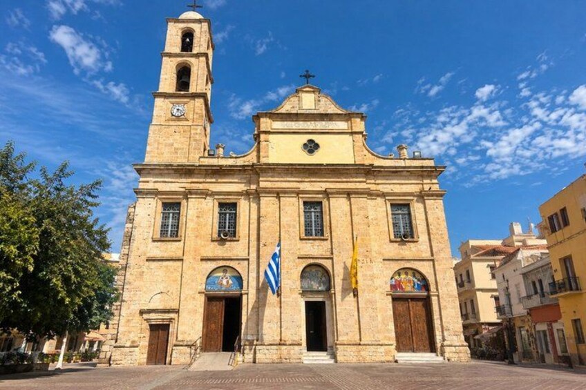 A historic church with a bell tower, a large arched entrance, and a flag in front. 3