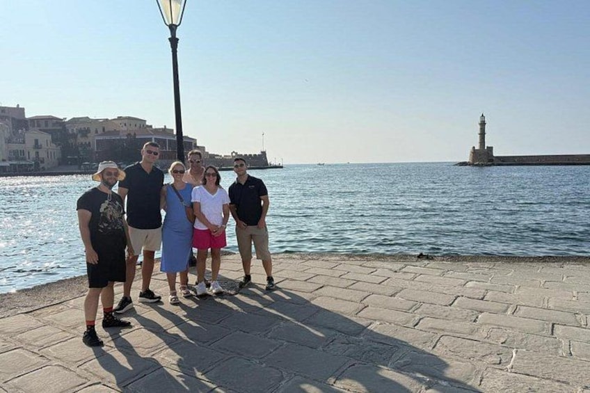 A group of people standing on a waterfront promenade with a lighthouse in the background. 5