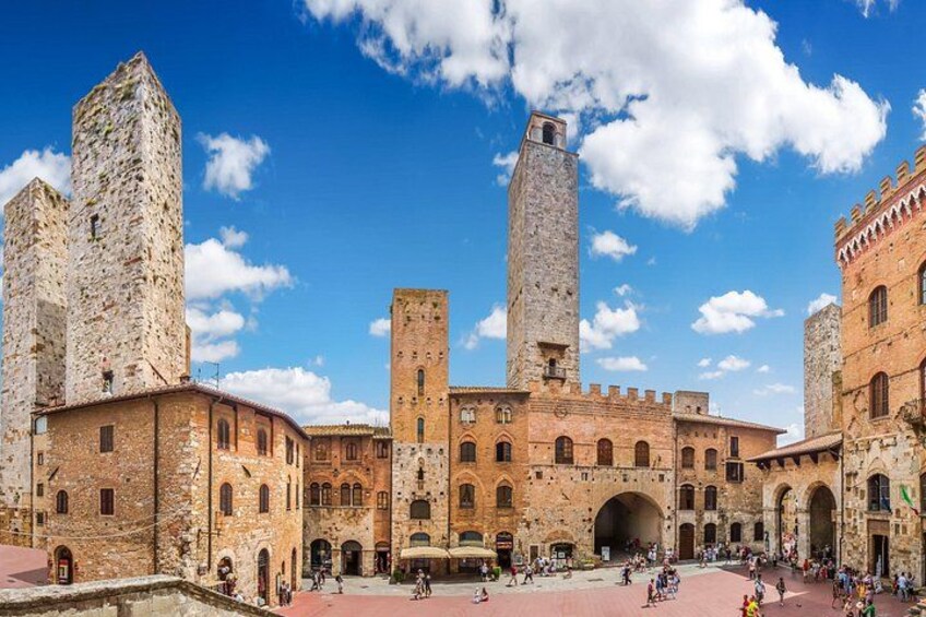 A historic stone building with multiple towers and arches, a central courtyard, and a clear blue sky. 5