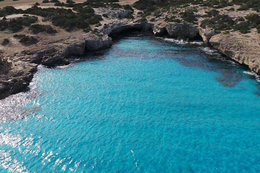 Un paysage côtier caractérisé par une mer bleue et limpide, des falaises rocheuses et une végétation clairsemée. 2