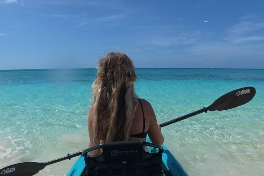 Una persona en kayak, con remo, frente a un mar azul y despejado. 1