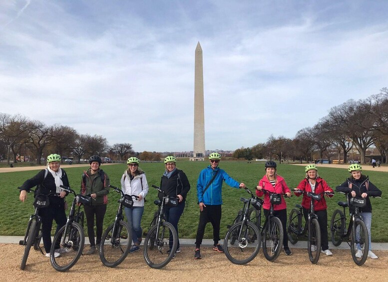 Un grupo de personas en bicicleta en un parque, con el Monumento a Washington al fondo. 2
