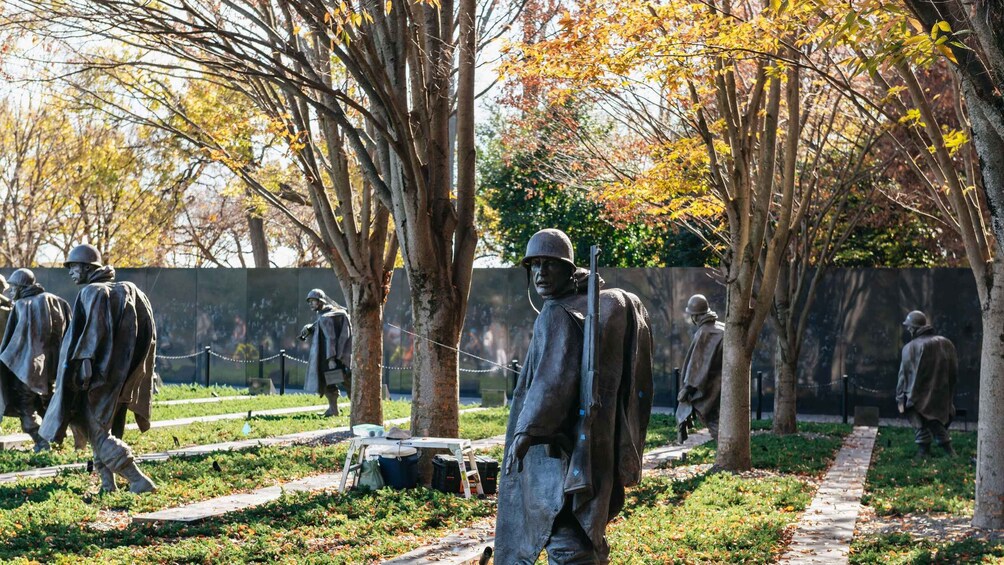 Un monumento con estatuas de bronce de soldados, rodeado de árboles y un sendero. 4