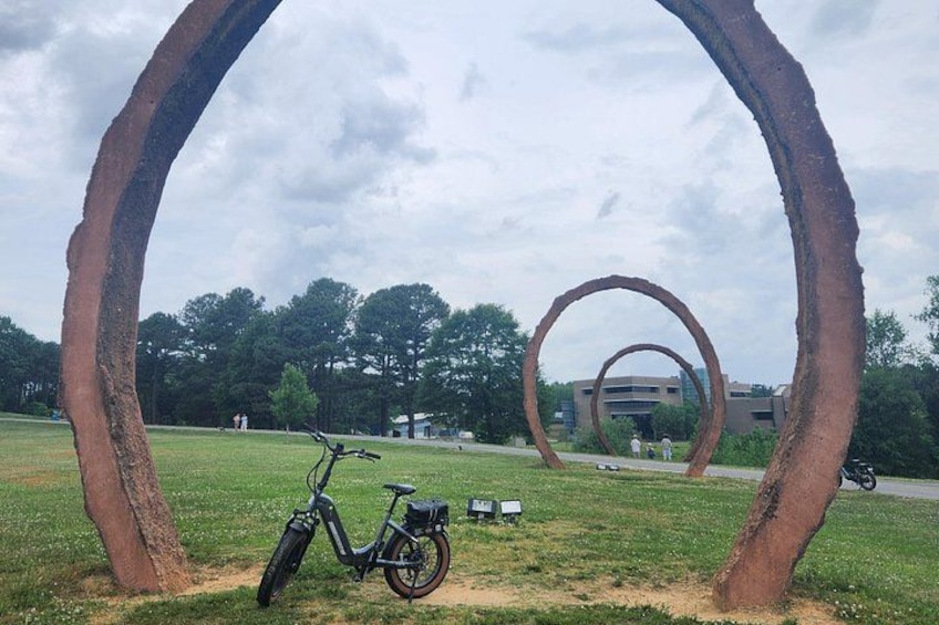 A bicycle, a large circular metal sculpture, and a building in the background. 3