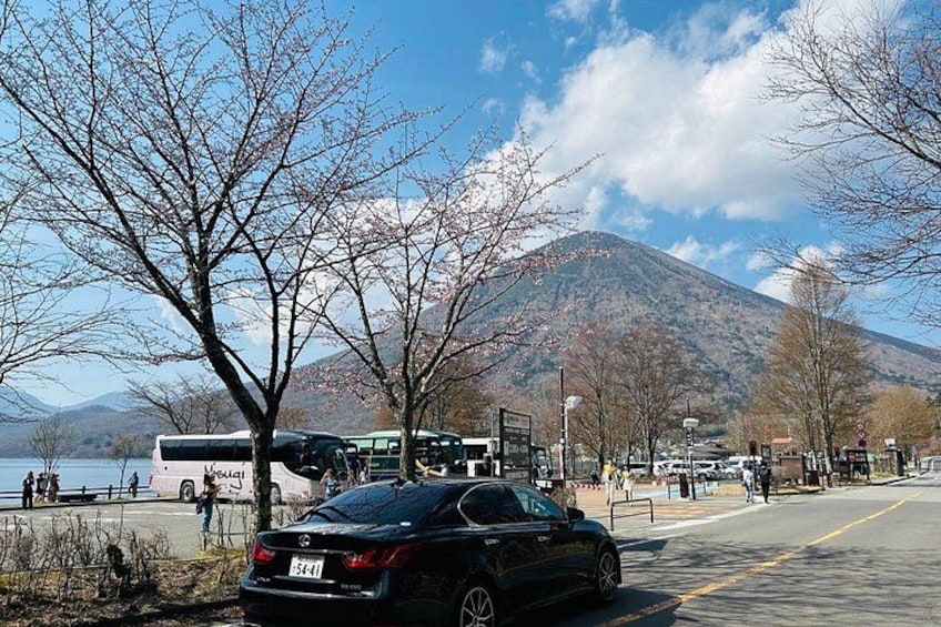 Un'auto parcheggiata su una strada, con una montagna e un lago sullo sfondo. 2