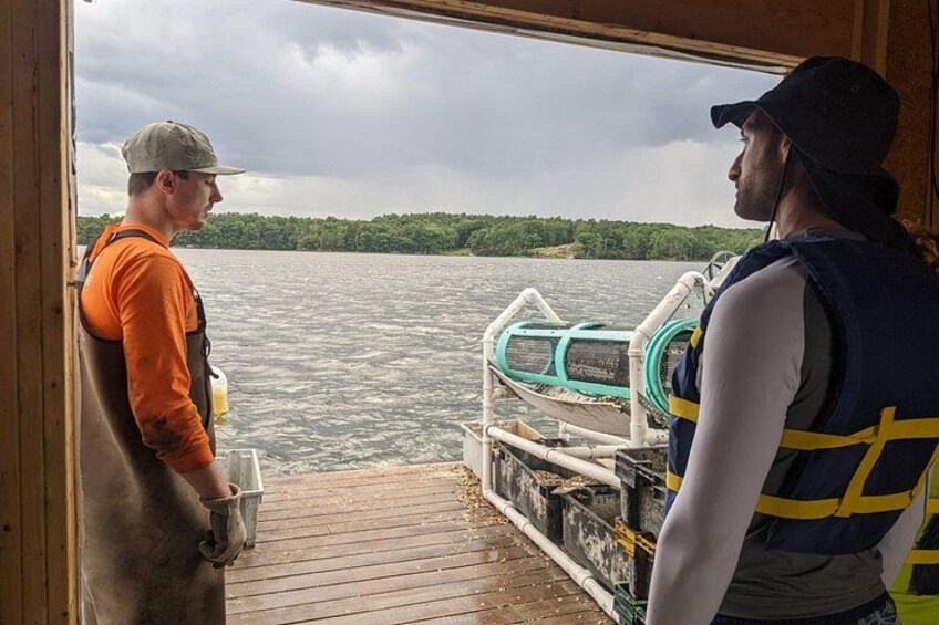Two people on a boat with a forested shoreline in the background. 3