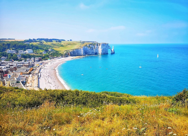 A coastal town with a beach, cliffs, and a clear blue sea. 4