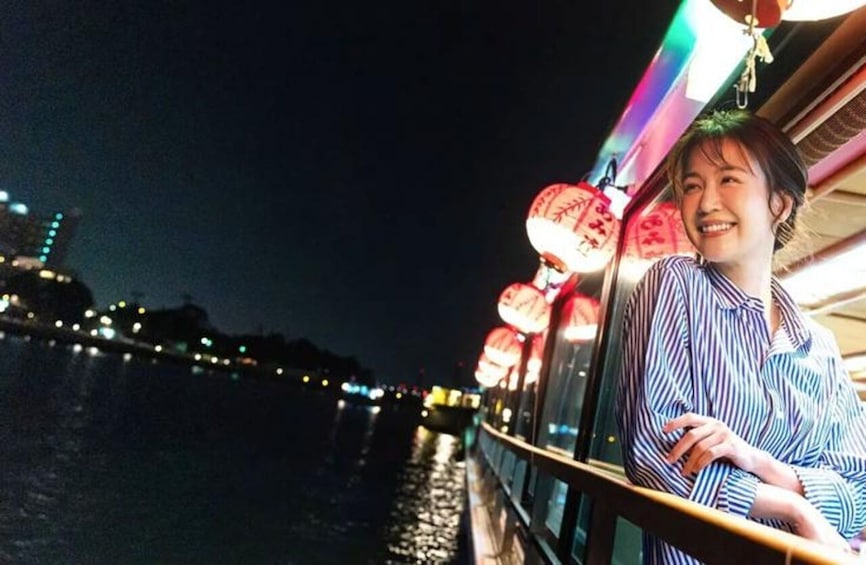 A person standing on a bridge at night with illuminated lanterns and city lights in the background. 3