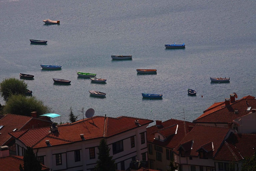 A coastal town with red-roofed buildings and several small boats on the water. 5