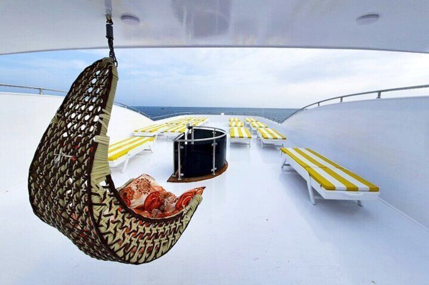 A deck with yellow-striped lounge chairs and a hanging chair. 2