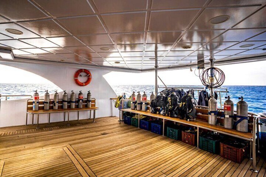 A boat deck with wooden flooring, life jackets, and scuba gear. 5