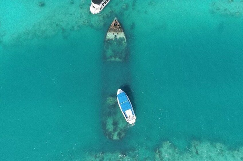 An aerial view of two boats anchored near a submerged structure in clear turquoise water. 1