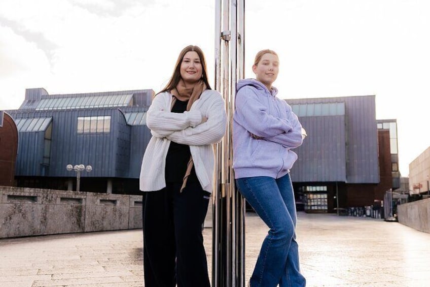 Two people standing on a rooftop with a modern building in the background. 2