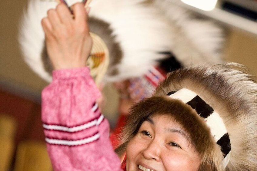 A person wearing a pink jacket and a headband with feathers. 3