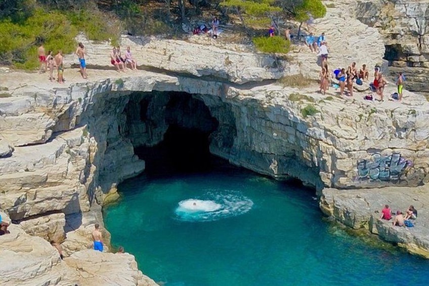 A rocky coastal area with a natural pool surrounded by people. 3