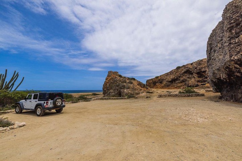 A white off-road vehicle parked on a dirt road with a rocky landscape and a clear sky. 2