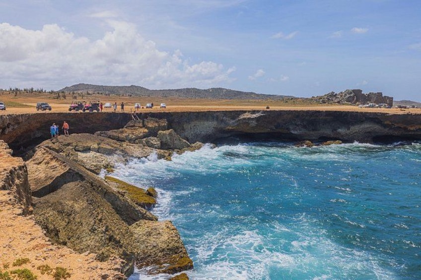 A coastal landscape with rocky cliffs, a sandy beach, and a clear blue sea. 4