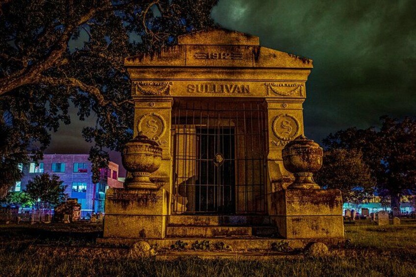 A stone monument with the name 'SULLIVAN' at night, surrounded by trees and illuminated by artificial lighting. 5
