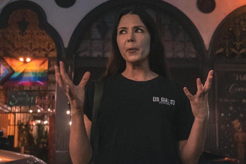 A person in a black t-shirt with 'US GHST' text, standing in front of a stained glass window with a rainbow design. 4