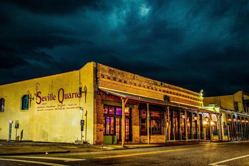 Un edificio con la señalización 'Seville Quarter', una calle y un cielo oscuro. 1