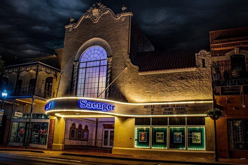 A theater with a marquee displaying 'Saenger' and a list of shows. 3