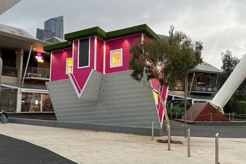 Un bâtiment au design unique, aux couleurs rose et gris, doté d’un toit végétalisé et d’un arbre planté devant. 4