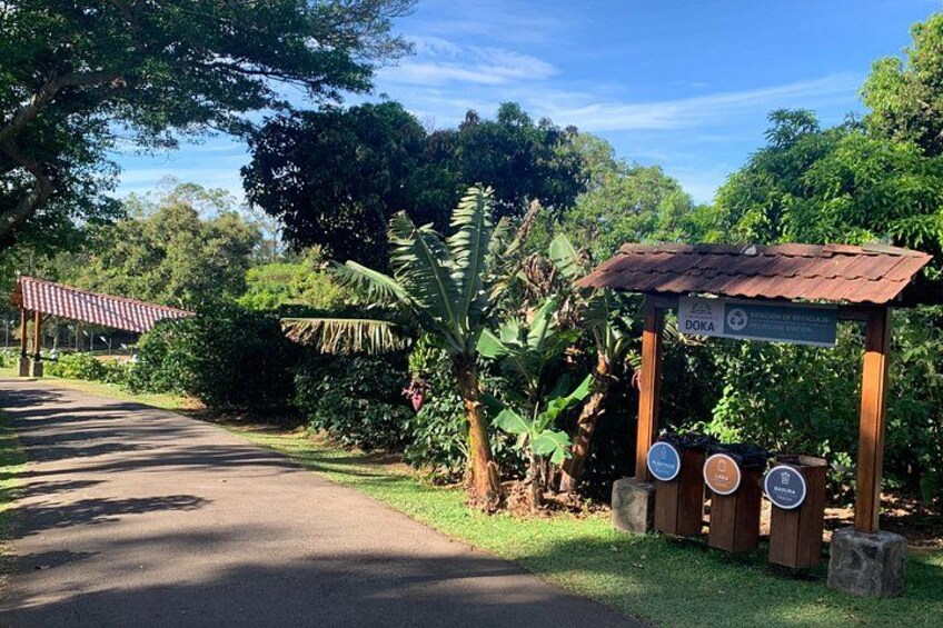 A rural road with a wooden shelter labeled 'DOKA' and a sign indicating a 'PARKING' area. 3