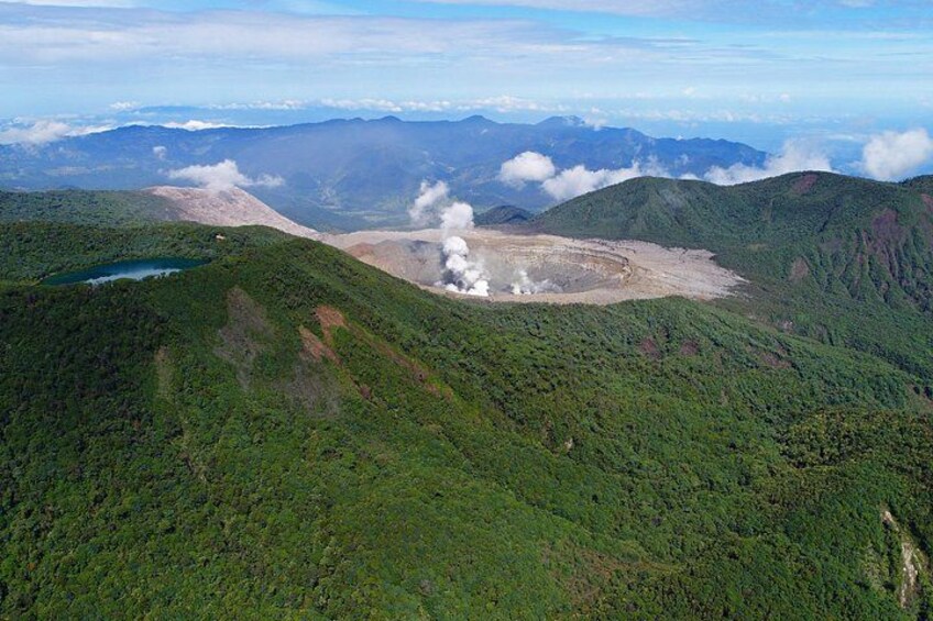 A mountainous landscape with a lake, forested areas, and a geothermal area with steam. 2