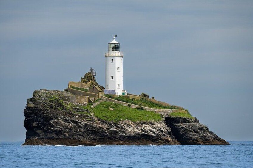 A lighthouse on a rocky island with a grassy path leading to it. 3